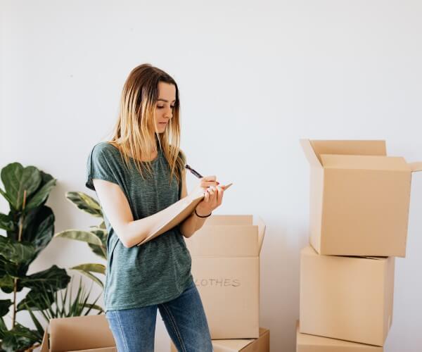 woman writing on papers with open moving boxes behind her